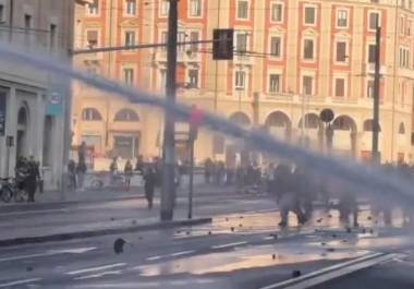 La mujer caminaba con paso firme cerca del frente de la multitud, vestida con ropa llamativa, antes de que un chorro directo de agua a alta presión la arrojara al suelo.