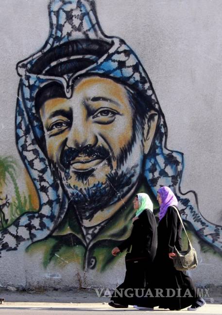 $!Dos estudiantes pasan junto a una pared con un graffiti del desaparecido presidente palestino, Yaser Arafat, en Gaza, en la franja de Gaza.