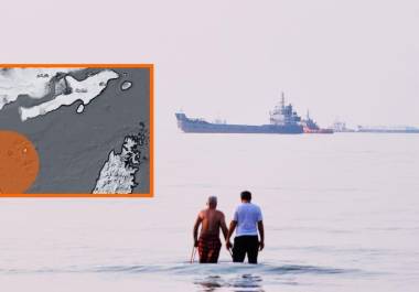 Dos hombres caminan en las aguas del estrecho de Ormuz con barcos fondeados más lejos, cerca de Bandar Abbas, Irán, el domingo 12 de julio de 2026, informó la AP.