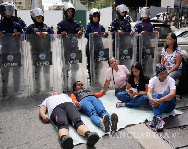 $!Familiares de presos políticos se tumban frente a la policía antidisturbios que custodia el centro de detención Zona 7 en Caracas.