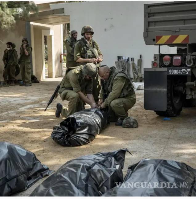 $!Soldados israelíes revisan bolsas con restos de comandos de Hamás en el kibutz Kfar Aza, en la frontera con Gaza.