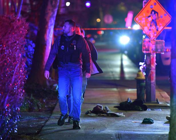 Un policía pasa entre prendas de ropa en una acera cerca de la entrada de la Universidad de Brown, durante la investigación del tiroteo.