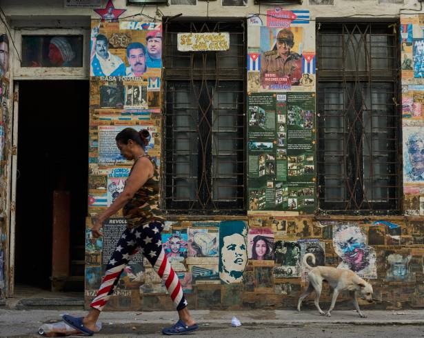 Una mujer pasa junto a un edificio en el que se exhiben fotografías del expresidente cubano Raúl Castro y del expresidente venezolano Nicolás Maduro, en La Habana, Cuba.