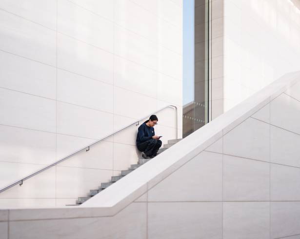 Una mujer revisa su teléfono sentada en una escalera afuera de un centro comercial en Beijing, China, el jueves 15 de enero de 2026.