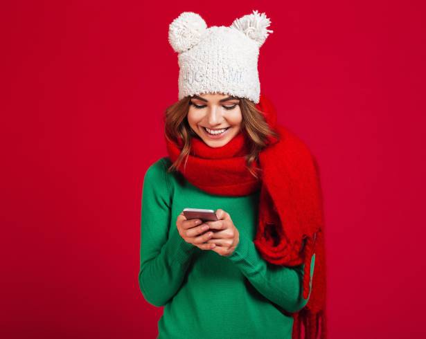 Image of cute pretty young woman wearing hat and scarf. Looking aside chatting by phone.