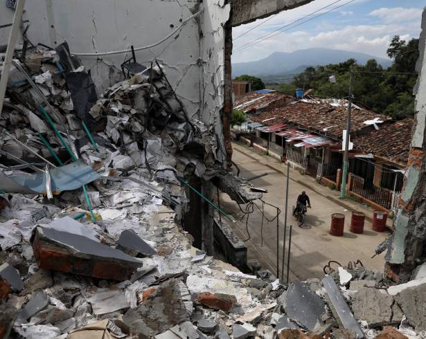 Un hombre pasa en motocicleta junto a las ruinas de casas destruidas cinco meses antes en un ataque de disidentes de las antiguas Fuerzas Amadas Revolucionarias de Colombia en Buenos Aires, Cauca, Colombia.