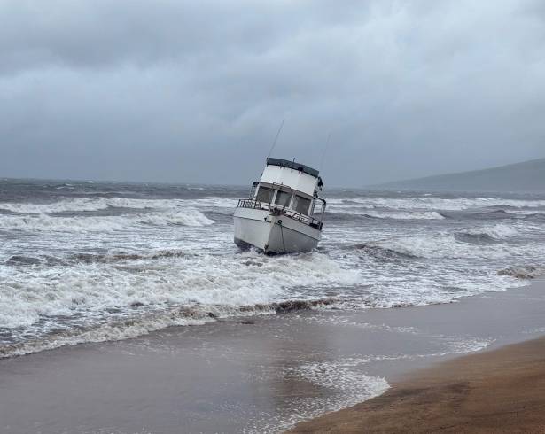 En esta foto proporcionada por el condado Maui, un barco está encallado en una playa frente a Kihei, Hawai, durante una fuerte lluvia.