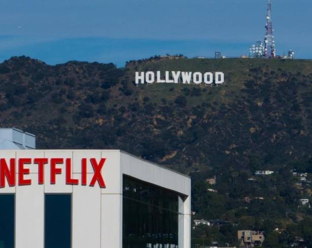 Un letrero de Netflix en la azotea de un edificio en Los Ángeles con el cartel de Hollywood a lo lejos.