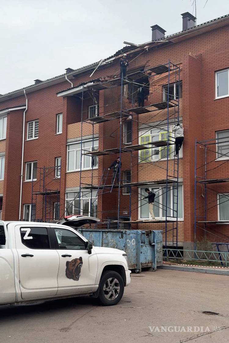 $!Unos hombres trabajan en la reparación de un edificio de apartamentos que resultó dañado durante un ataque con drones ucranianos en Sofino, Rusia.
