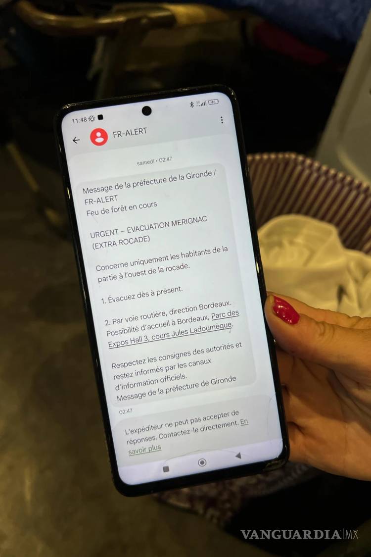$!Morgane Bonichot vacuada y refugiada en un centro de evacuación en Burdeos, Francia, muestra un mensaje de evacuación que recibió en su teléfono móvil.