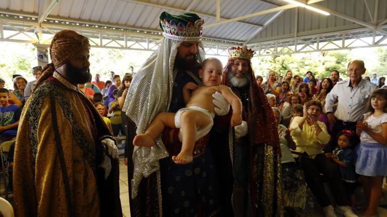 $!Los tres Reyes Magos levantan a Wilfredo Mateo Díaz, quien interpreta al niño Jesús en el Centro Capuchino de Trujillo Alto en San Juan, Puerto Rico. EFE/Thais Llorca