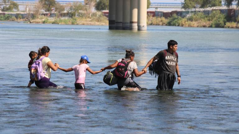 $!Una familia hace cadena para cruzar las aguas del río Bravo y entregarse a las autoridades de Estados Unidos.