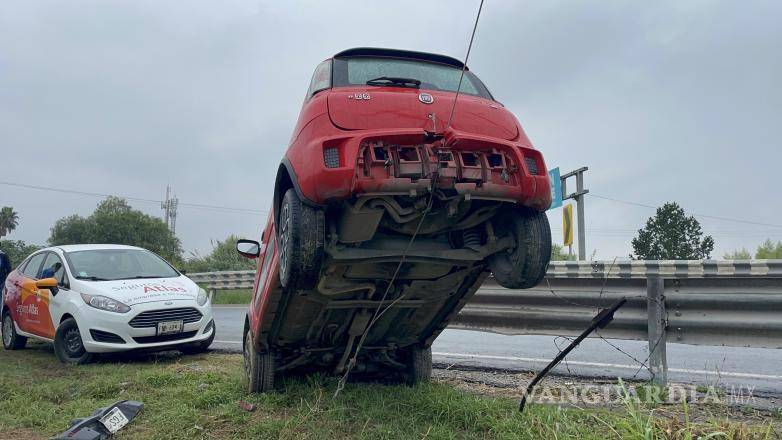 $!El vehículo Fiat Uno quedó suspendido sobre el cable tensor de un poste, evitando su caída al arroyo.