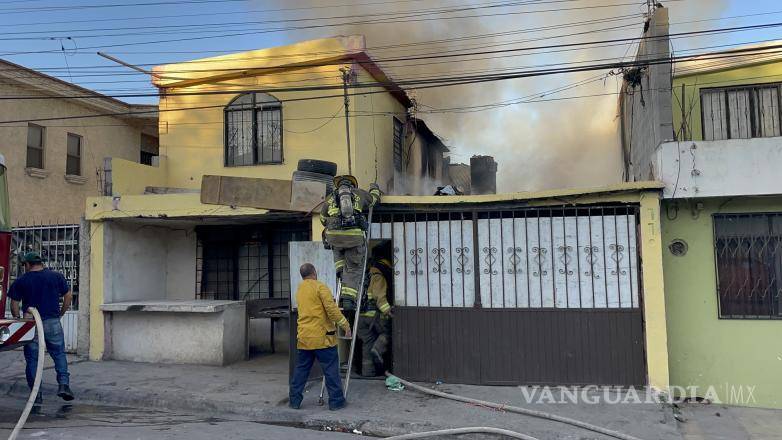 $!Los bomberos combaten las llamas desde lo alto de la casa, donde se encontraban bolsas llenas de ropa y muebles.