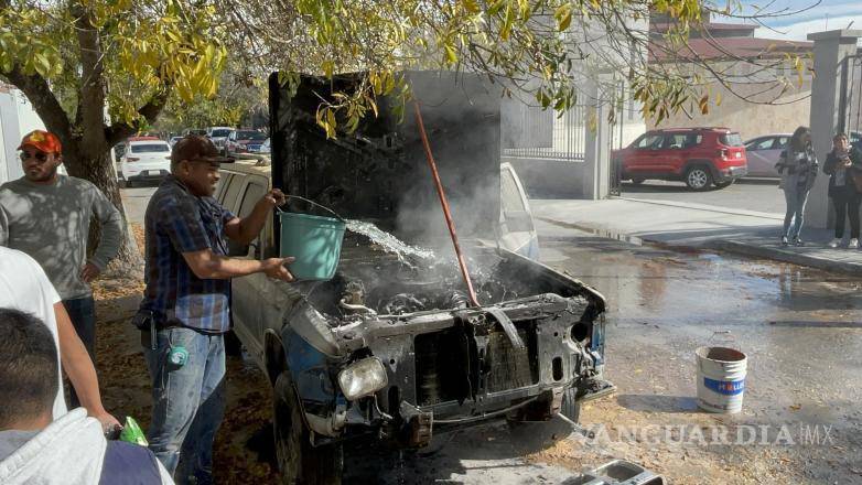 $!Ciudadanos utilizando cubetas de agua y extintores maniobran para sofocar las llamas de la camioneta Chevrolet Blazer modelo 1993.