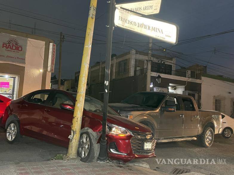 $!Tras el fuerte choque entre un automóvil Chevrolet color guindo y una camioneta Ford Lobo, el vehículo compacto quedó atrapado contra un poste de nomenclatura municipal.