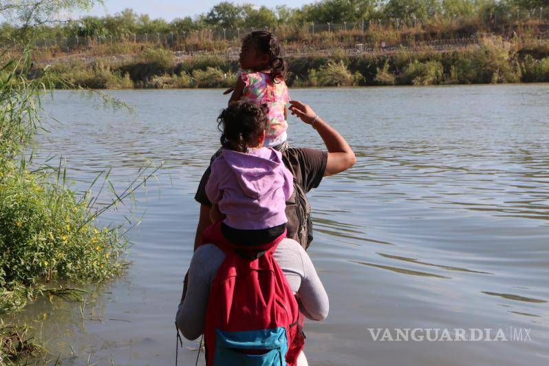 $!Una familia cargando en los hombros a sus dos pequeñas se dispone a cruzar el río Bravo.