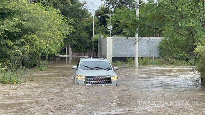 $!La camioneta GMC color gris quedó varada en el encharcamiento tras intentar cruzar el vado inundado.