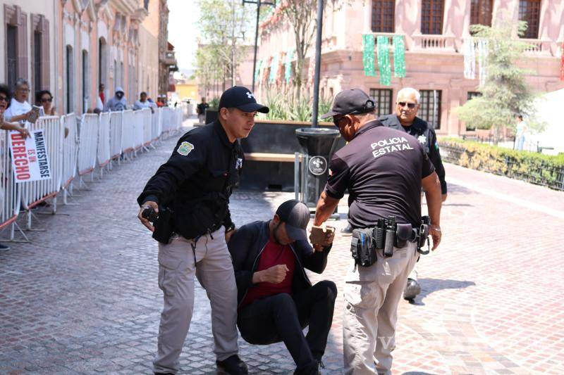 $!Policías del Palacio de Gobierno detienen con violencia al joven activista Jonathan Palacios después de que cruzara las vallas que cercaban la plaza.