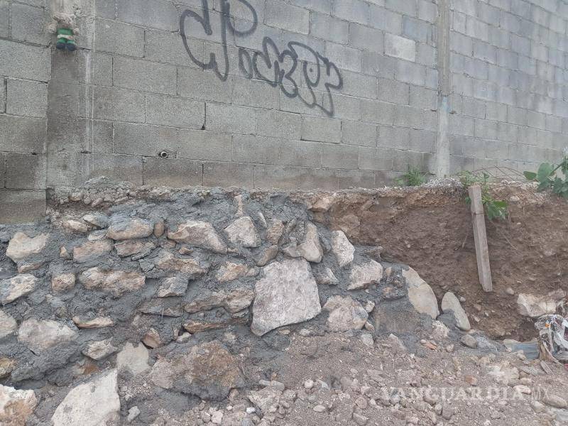 $!Barda caída en predio vecino por socavón generado cerca de obras inconclusas.