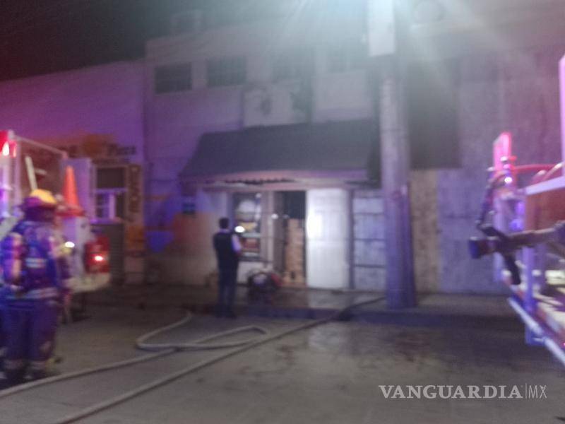 $!La confusión entre fumigación e incendio obliga a los bomberos a ingresar al bar La Reliquia en el centro de Saltillo, generando daños en la puerta de acceso.