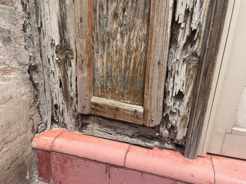 $!The original door of the house has been replaced by a new door, and the frame shows considerable wear.