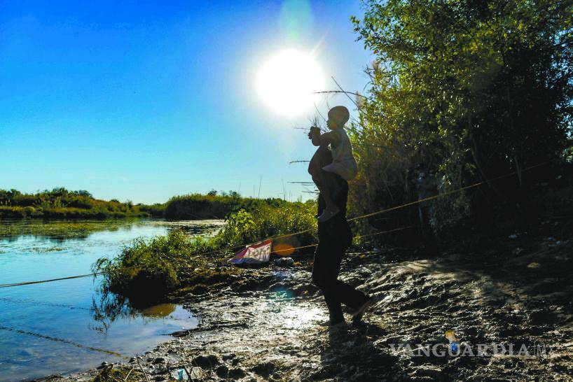 $!Al pie del Río Bravo, un migrante carga en sus hombros a un niño y ambos dirigen su mirada al otro lado del agua, hacia el anhelado sueño americano.