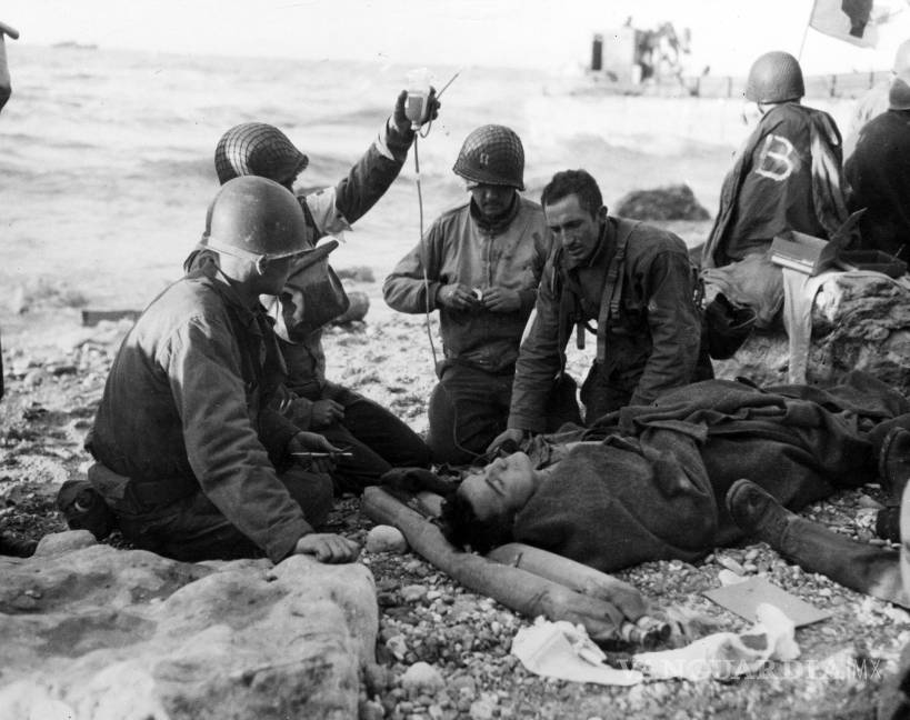 $!El personal médico del ejército estadounidense administra una transfusión de plasma a un soldado herido frente a la costa de Normandía, Francia.