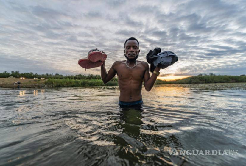 $!Migrante posa al amanecer sujetando sus pertenencias en la línea fronteriza que cruza el río. Foto: Omar Saucedo