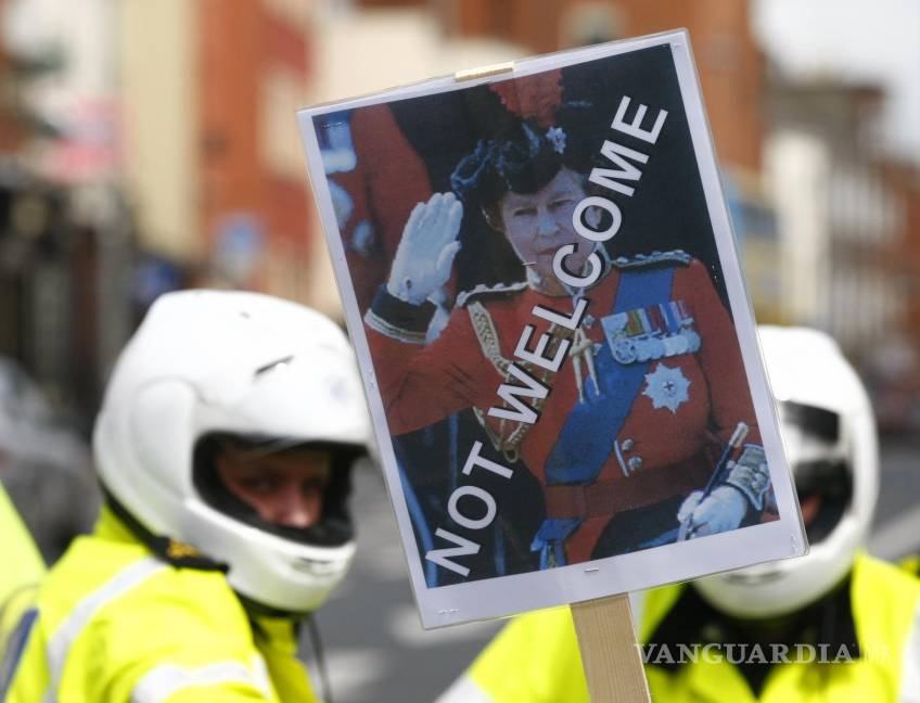 $!Un manifestante sostiene una pancarta con la imagen de la reina Isabel II frente a la policía en Dublín el 17 de mayo de 2011. AP/Tim Hales