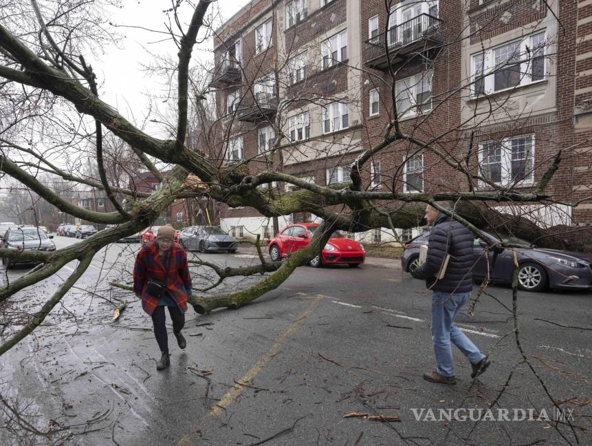 $!Peatones caminan entre los escombros en Montreal después de que una tormenta invernal dejó a más de un millón de clientes sin electricidad en Quebec.