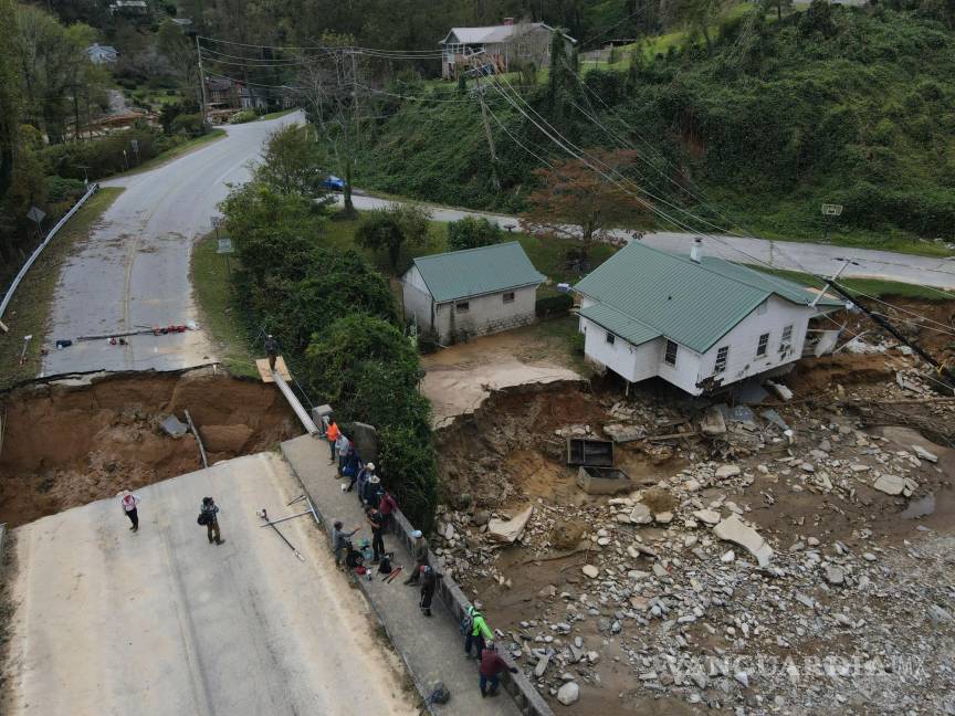 $!La gente se reúne en un puente dañado sobre el río Broad en la autopista 64 en la comunidad Bat Cave de Carolina del Norte.