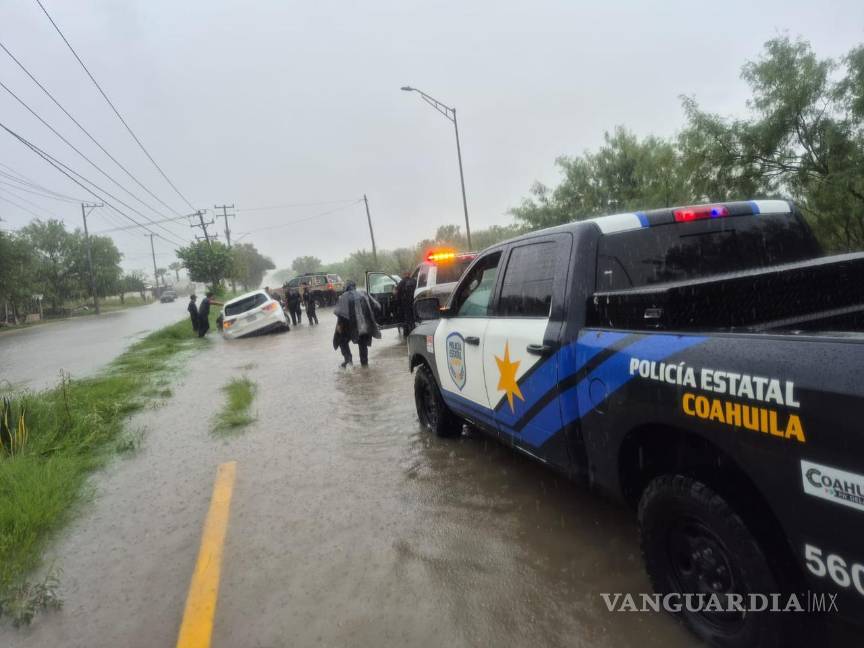 $!Personal de Protección Civil y vecinos colaboran para rescatar a conductores atrapados por la corriente en calles inundadas de Piedras Negras.