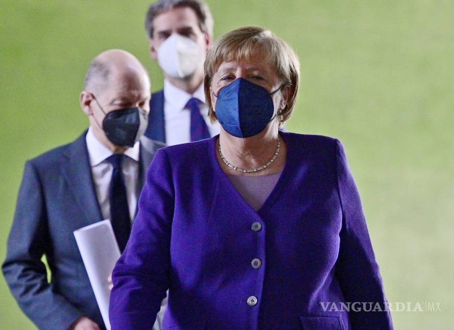 $!La canciller alemana Angela Merkel, seguida por el ministro de finanzas Olaf Scholz, izquierda, arriba a una conferencia de prensa en Berlín. AP/John Macdougall