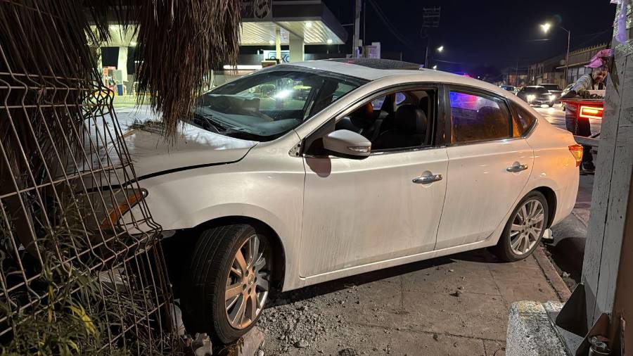 El Nissan Sentra quedó sobre la banqueta tras impactar la base del estacionamiento.