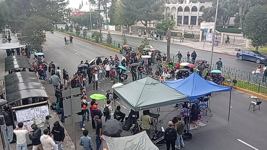 Estudiantes del TecNM resguardan el bloqueo sobre la Carranza con carpas improvisadas ante la lluvia.