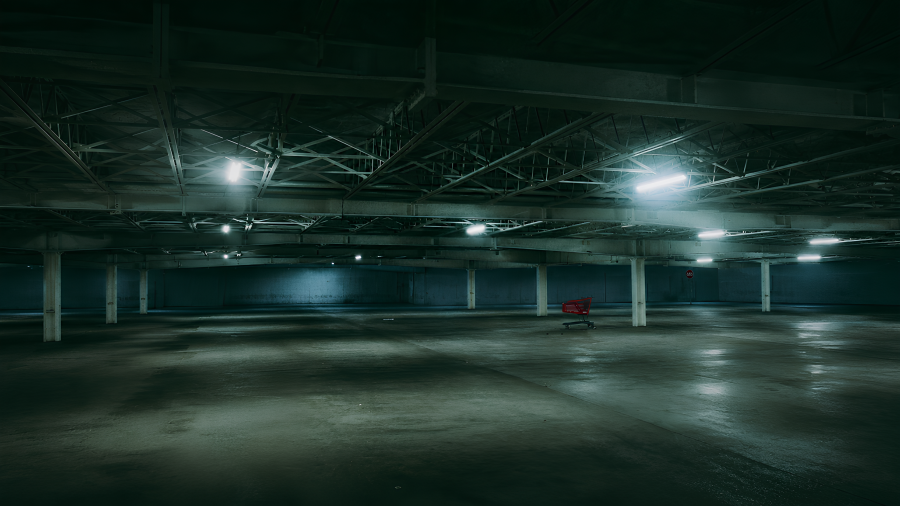 Un carrito abandonado basta para alterar el sentido de un estacionamiento vacío: la luz sigue encendida, las columnas siguen en pie, pero el lugar ya no parece esperar autos, sino algo más.
