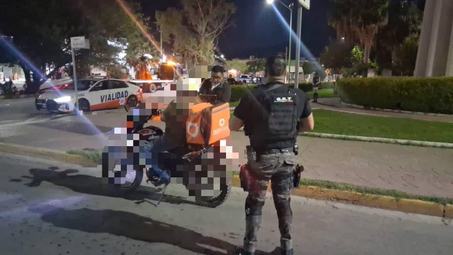 Agentes de Tránsito y del Grupo de Reacción realizan la revisión de una motocicleta durante un operativo nocturno.