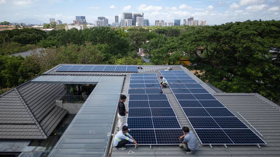 Un equipo de instaladores solares instaló un nuevo sistema de paneles solares en el tejado de una vivienda en Manila, Filipinas.