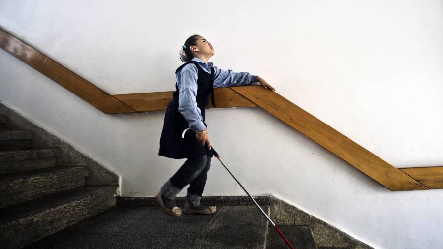 En la imagen, una niña ciega se ayuda de un bastón para bajar las escaleras.