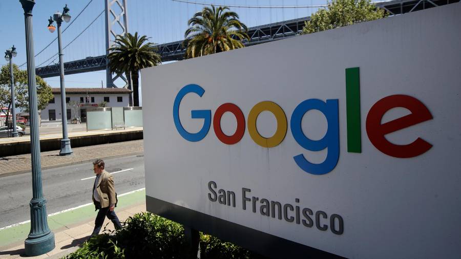 En esta foto de archivo del 1 de mayo de 2019, un hombre pasa caminando frente a un letrero de Google, con un tramo del puente de la Bahía (Bay Bridge) al fondo, en San Francisco.