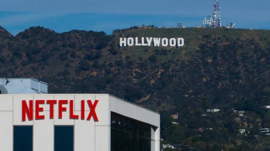 Un letrero de Netflix en la azotea de un edificio en Los Ángeles con el cartel de Hollywood a lo lejos.