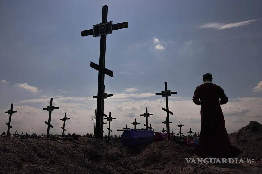 $!En la imagen, un sacerdote ortodoxo ante un a fosa común en Bucha en agosto de 2022.