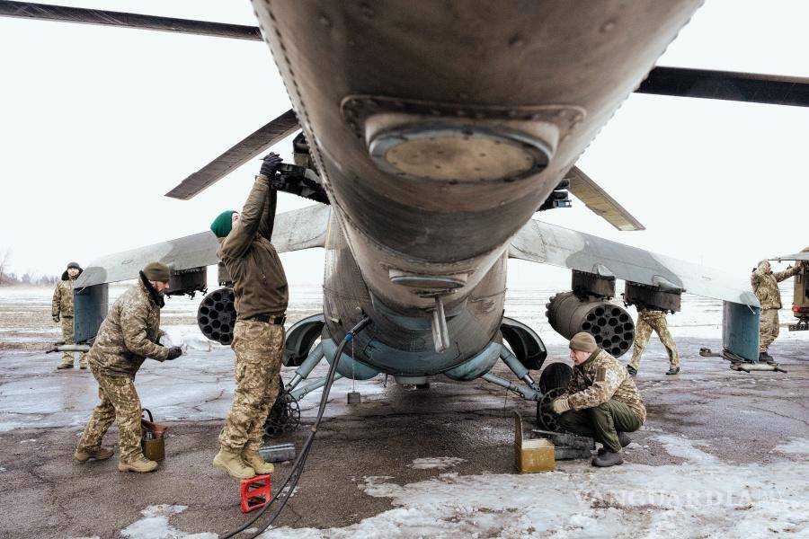 $!Los miembros de la tripulación de tierra de la 18.ª Brigada Sikorsky reabastecen un helicóptero de combate con cohetes antes de una misión en el este de Ucrania en febrero de 2023.