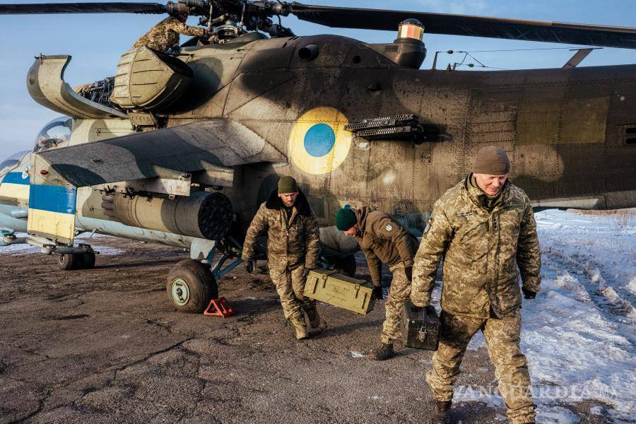 $!Los miembros de la tripulación de tierra de la 18.ª Brigada Sikorsky reabastecen un helicóptero de combate con cohetes antes de una misión en el este de Ucrania.