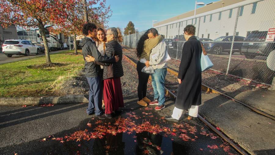 Inmigrantes de Portland, incluido Victor Cruz, en el centro a la derecha con la sudadera gris, abrazan a familiares tras ser liberados bajo fianza en Tacoma, Washington, el viernes 7 de noviembre de 2025.