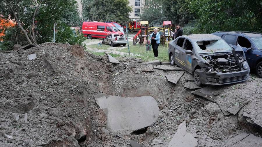 Residentes locales permanecen cerca de un cráter y de automóviles dañados por un ataque con misiles rusos en Kiev, Ucrania, el lunes 6 de julio de 2026. (Foto AP/Efrem Lukatsky)