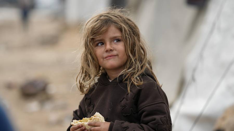 Una niña sostiene un emparedado en un campamento de tiendas de campaña para palestinos desplazados en la playa de la Ciudad de Gaza, el miércoles 10 de diciembre de 2025.