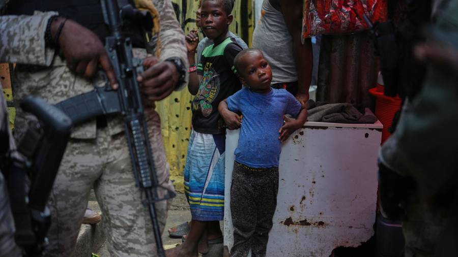 Niños al lado de policías, durante la visita de la delegada del Programa Mundial de Alimentos, la princesa Sarah Zeid de Jordania, en un refugio para familias desplazadas en Puerto Príncipe, informó AP.