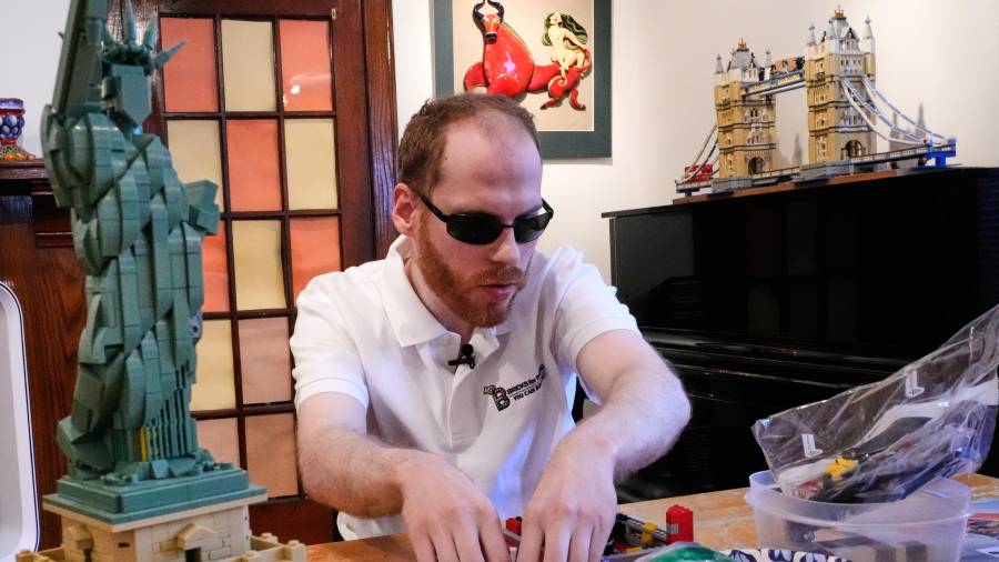 Matthew Shifrin, fundador de Bricks for the Blind, palpa piezas específicas mientras construye una máquina expendedora de chicles a base de piezas de Lego en la casa de su familia en Newton, Massachusetts.
